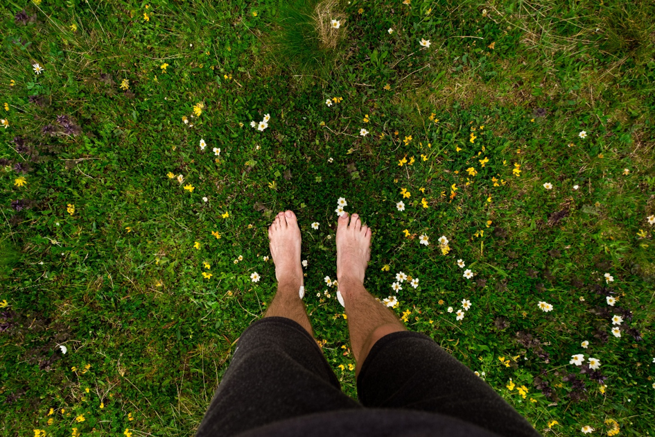 man staat met blote voeten op gras