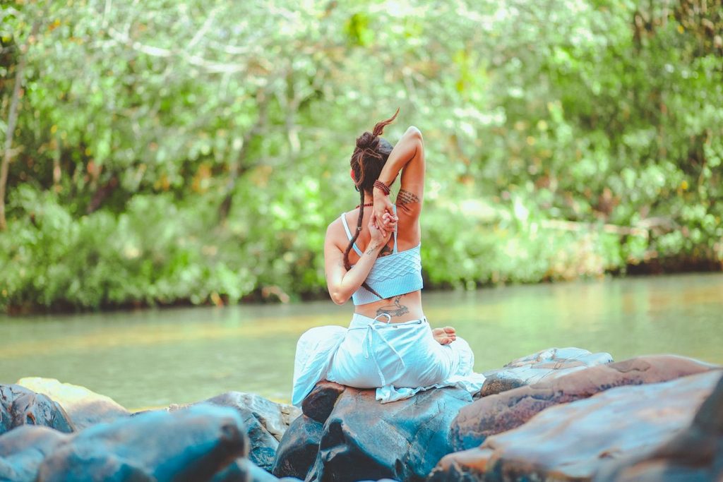 vrouw die yoga uitvoert langs het water